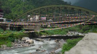 23 Temmuz 2025 Uttarakhand Hindistan. Badli Nehri üzerindeki köprü, Sahastradhara Dehradun 'da bir şarkı kolu, renkli dua bayrağıyla süslenmiş.
