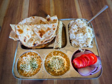 Çapati, pirinç, dal ve metal tepside dilimlenmiş sebzeli Hint thali..