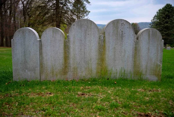 Farklı Boyutlarda Beş Kemerli Gri Mezar Taşı Çimenli Bir Mezarlıkta — Stok fotoğraf
