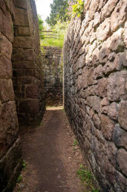 Uzun kahverengi taş duvarlar, aralarında gizli bir koridor oluşturur. Duvarlar, labirent ya da labirent gibi çıkmaz sokak gibidir. Duvarlar büyük ve güzel ama bunaltıcı..