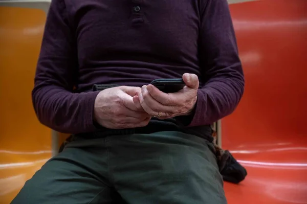 Белый Мужчина Смотрит Телефон Сидя Оранжево Красном Сиденье Метро Крупный — стоковое фото