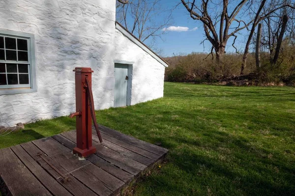田园诗般的乡村场景 一个古老的红色水泵在一个殖民的美国家庭前面 绿色的草地上 金色的时辰 阳光和长长的阴影 宾夕法尼亚Idyllic Hopewell Furnace — 图库照片