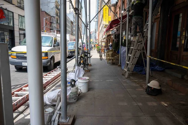 足場のオーバーヘッドと建設資材とニューヨーク市の歩道 車の歩行者やビジネスの兆候で忙しい通り 晴れた日 — ストック写真