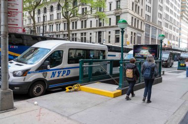 Manhattan New York sokak sahnesi metro girişinin yanında. New York Polis Departmanı 'nın minibüsü kaldırımda yürürken yanında parlak sarı çizme vardı. Kaldırımda yaya geçidi var. Sadece editör kullanımı.