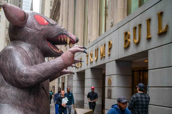 New York, New York, ABD 10-06-2023 kaldırım ve kaldırım taşı caddelerindeki kaldırım taşları New York 'un finans bölgesinde Trump Binası' nın önünde. Pençeleri, kırmızı gözleri ve keskin dişleri olan dev bir şişme fare kapının önünde girişe bakıyor.
