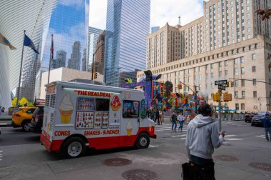 New York, New York, ABD 04-26-2023 Urban caddesi kavşağında renkli dondurma kamyonu, Oculus ve WTC arka planda. Yayalar, bayraklar, gökdelenler, yaya geçidi. Sadece editör kullanımı.