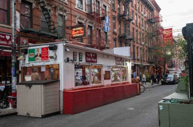 Little Italy, New York, New York, ABD 11-09-2023 The Heart of Little Italy restoranı kaldırım kenarındaki oturma alanı büfesini yayalar, arabalar, binalar ile dolu New York sokağı arka planıyla kapladı.