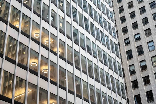 Background image of two Manhattan office buildings at odd corner angle with rows of windows and interior circular lights. Stress concept overwhelmed, work, mental illness, confusion also. No people.
