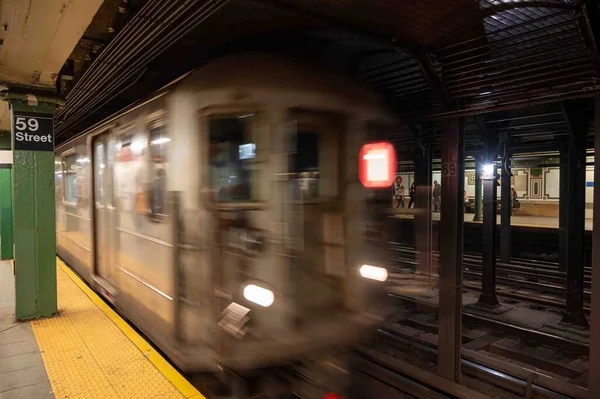 New York, New York, ABD 05-11-2023 metro istasyonu 59. caddedeki yeşil sütunu ve sarı güvenlik hattı olan metro istasyonu. Metro vagonu platforma hareket bulanıklığıyla geliyor..