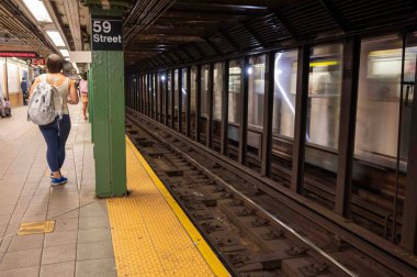 Bulanık tren raylardan geçerken 59. Cadde metro istasyonunda bekleyen yolcular. Sadece editör kullanımı