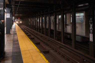 New York, New York, ABD 02-22-2023 treni 86. caddedeki metro istasyonuna varır. Sarı güvenlik hattı ve çelik kirişler görünür ve tren zıt istikamette ilerler. Sadece editör kullanımı.