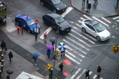 New York, New York, ABD 05-15-2024 Manhattan caddesinin yaya geçitleri, trafik ışıkları ve kaldırımlı kavşağı. İnsanlar şemsiye tutuyor, fotokopi alanı da var. Sadece editör.