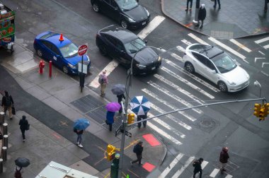 New York, New York, ABD 05-15-2024 Manhattan caddesinin yaya geçitleri, trafik ışıkları ve kaldırımlı kavşağı. İnsanlar şemsiye tutuyor, fotokopi alanı da var. Sadece editör.