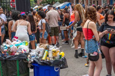 Philadelphia, PA, USA 06-02-2024 Çöp Kutuları ve geri dönüşüm kutuları ön planda. Onur Festivali sırasında arka planda mutlu ve güzel insanlar var. Sadece editör kullanımı