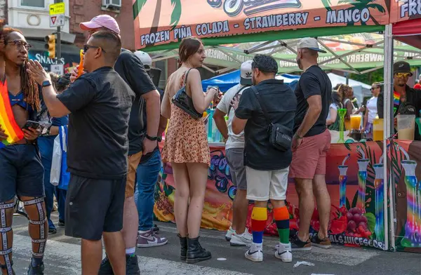 stock image Philadelphia, PA, USA 06-02-2024 Friends gather in front of frozen juice drink stand vendor at Pride Fest urban street festival. Diversity gay lesbian pride concepts. Editorial use only