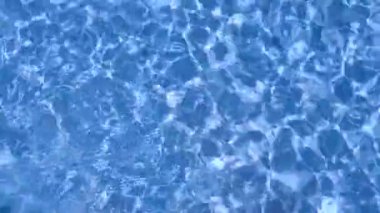 Yüksek açılı hipnoz görüntüleri. Sakin, berrak mavi su, ışık kırılması ve dalgalanmalar. Günışığı temalı tatil temalı havuz meditasyonu spa merkezi hafta sonu havuz temizleme konsepti.