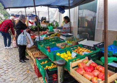 Silves, Portugal, 04-05-2025 Algarve müşterileri sebze ve meyve almak için açık hava çiftçi tezgahından domates, elma, mango, armut, muz, soğan kutularına