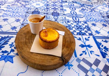 Silves, Portekiz, 04-05-2025 ahşap bir Portekiz masa üstü ve tarçın çubuklu espresso kahvesi ve fotokopi saplı bir alentejanito pastası. Yazı