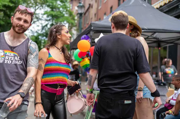 Philadelphia, PA, ABD, 06-02-2024 Gökkuşağı tişörtlü bir kadın kalabalık bir caddede Onur Festivali sırasında başkalarıyla konuşuyor.