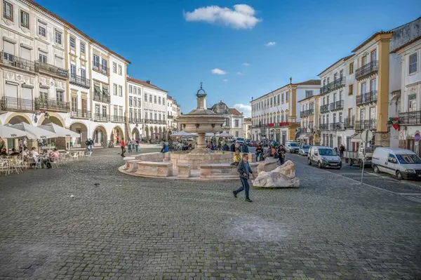 Evora, Alentejo, Portekiz 11-19-2024 Meşgul kaldırım taşı sokak sahnesi kasaba meydanı Giraldo do. Yayalar, antik çeşmeler ve mavi gökyüzünün altındaki binalar.