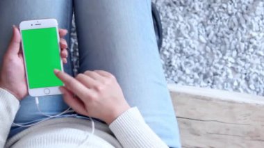 Kadın kafede otururken yeşil ekranlı tablette müzik dinliyor.