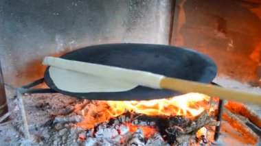 Ekmek pişiren kadın ekmek pişirmek için yakacak odun yakıyor.