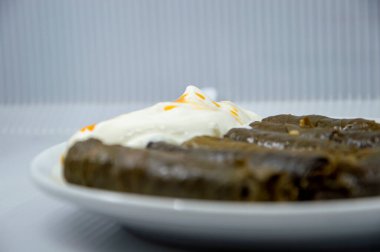 Pirinçten yapılmış dolması sarmak ve sarmaşık yapraklarına kıyma, yanında yoğurt.