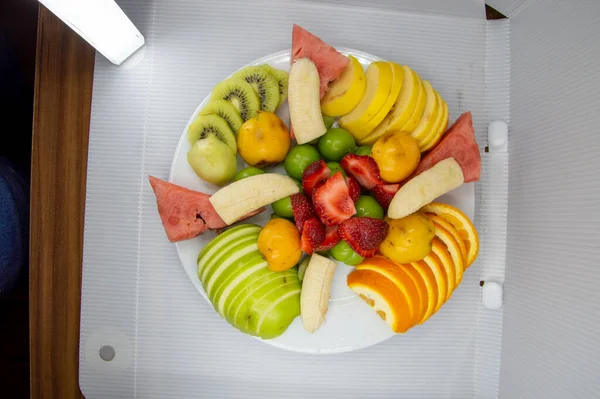 Bir tabak elma, portakal, karpuz, kivi, muz ve çilek.