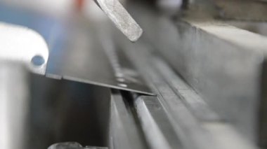 Fabrikada çalışan bir işçi, metal levhaları hidrolik bükme makinesiyle büküyor.