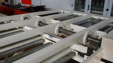 Robot kol demir çarşafları başka bir makineye taşıyor.
