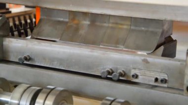 Fabrikada çalışan bir işçi, metal levhaları hidrolik bükme makinesiyle büküyor.