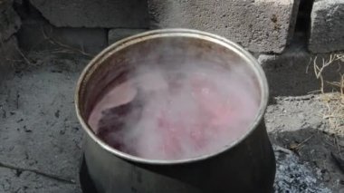 Ahşap yakılmış siyah bir kazanda kaynayan nar suyu.