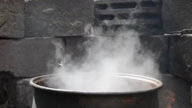 Ahşap yakılmış siyah bir kazanda kaynayan nar suyu.