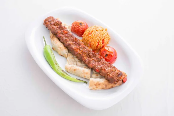 adana kebabı servis sırasında domates, pita, biber ve bulgur pilavı ile servis edilir.