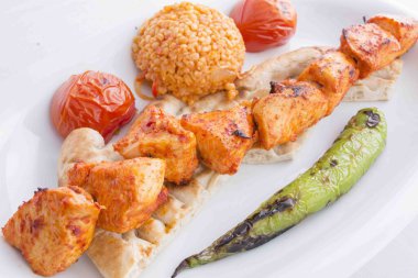 kebab served with tomato, pita, pepper and bulgur pilaf during service clipart