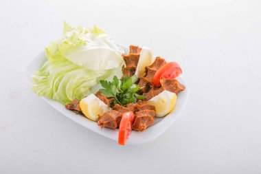 Lezzetli ve acı bir Türk yemeği marul ve limonla servis edilir, bulgur, domates ezmesi ve baharatla servis edilir..