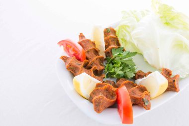 Lezzetli ve acı bir Türk yemeği marul ve limonla servis edilir, bulgur, domates ezmesi ve baharatla servis edilir..