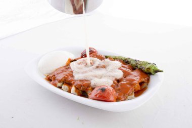 Servis sırasında domates, pide, biber ve tereyağı soslu ızgara kebap.