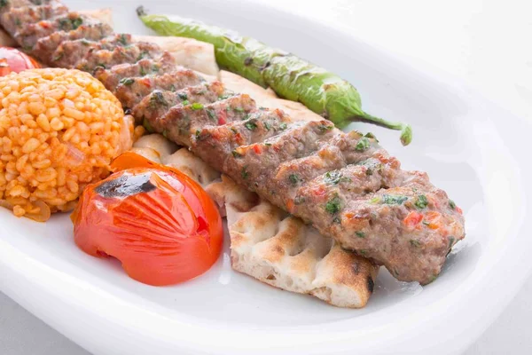 urfa kebabı servis sırasında domates, pita, biber ve bulgur pilavı ile servis edilir.