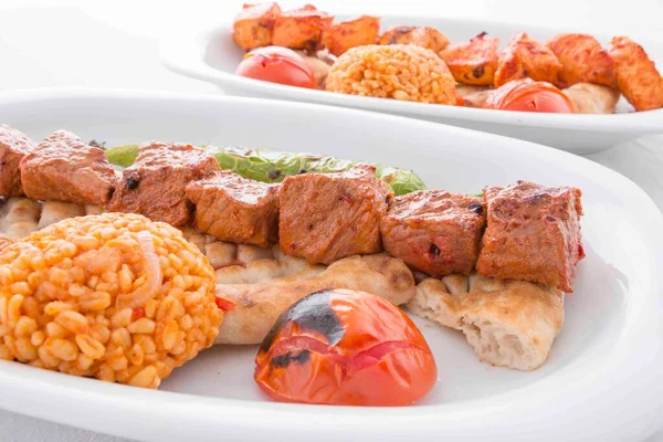 Servis sırasında domates, pita, biber ve bulgur pilavı ile servis edilen ızgara kırmızı et.