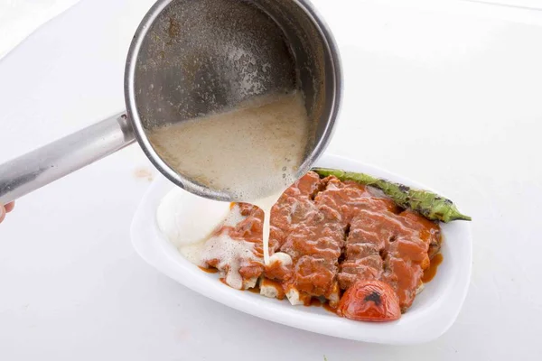 Servis sırasında domates, pide, biber ve tereyağı soslu ızgara kebap.