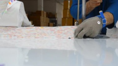 Tekstil fabrikasında büyük bir bıçakla kumaş kesiyor.