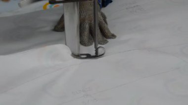 Tekstil fabrikasında büyük bir bıçakla kumaş kesiyor.