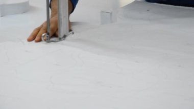 Tekstil fabrikasında büyük bir bıçakla kumaş kesiyor.