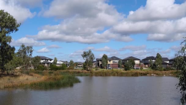 遠くにオーストラリア人の家や家がある住宅街に水の池があります コピースペース付きの背景テクスチャ オーストラリアの住宅市場と不動産投資の概念 — ストック動画