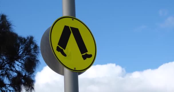 閉じる強い風の中で金属製のポール上の歩行者横断標識のアップ サインは オーストラリアの規格に準拠した黒い歩行シンボルを持つ黄色の背景を特徴としています メルボルン Vic Australia — ストック動画