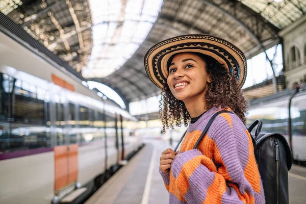 Young black woman traveler with backpack in the railway, Backpack and hat at the train station with a traveler. Travel concept. High quality photo