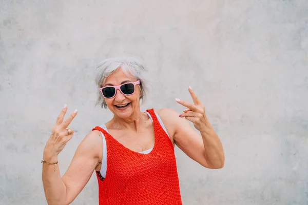 Positive Senior Female Sunglasses Red Knitted Top Showing Peace Gesture — Stock Photo, Image
