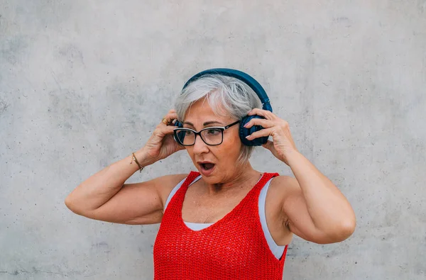 Šokovaný Seniorka Brýlích Červené Top Nastavení Sluchátka Při Poslechu Podcast — Stock fotografie