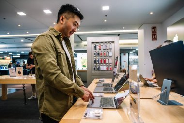 Alışveriş merkezinde ekrana bakarken yoğunlaşmış etnik erkek müşterinin netbook 'a bakmasının yan görünümü